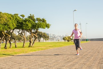 Focused sporty blonde jogging at promenade