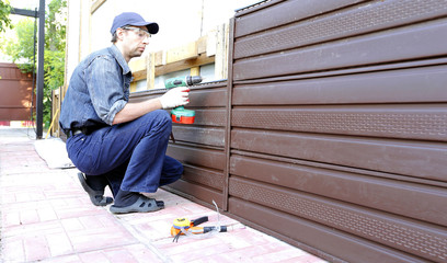 Worker installs plastic siding on the facade of the house