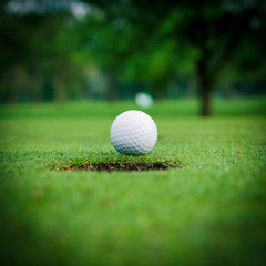 golf ball on lip of cup.  Golf ball and hole