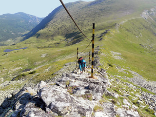 Obraz premium Young girl climbing by the safety rope on dangerous mountain slope