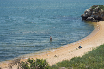 A man is going to a water of a wild cove in reserve Kazantip, Sea of Azov, Crimea
