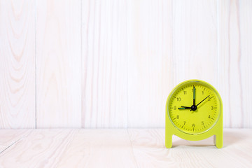 Green alarm clock on wood background
