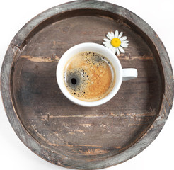Tasse Kaffee mit Blümchen auf rundem Tablett
