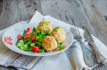 baked chickpeas balls with sesame and vegetable salad on a gray
