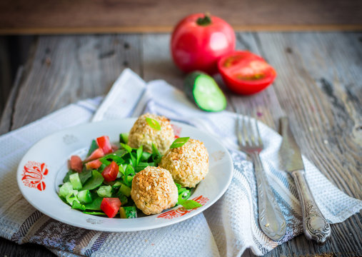 baked chickpeas balls with sesame and vegetable salad on a gray