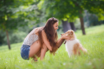Beautiful woman playing in the park with a small puppy collie