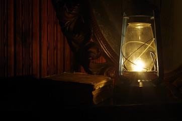 Book, oil lamp and mirror in the dark