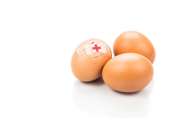 Concept of cracked egg with bandage next to two other eggs.