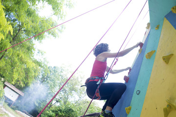 Girl exercise climbing on a artificial rock outdoors