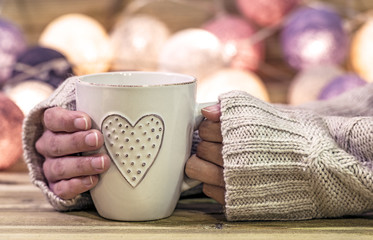 Hot cup (with heart), on wooden table, hands girl, and on shiny lights