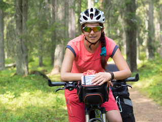 Woman riding a bike on the forest trail in sunny day
