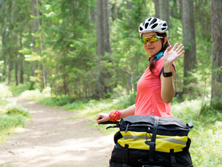 Woman riding a bike on the forest trail in sunny day