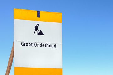 Dutch road maintenance sign against a blue sky