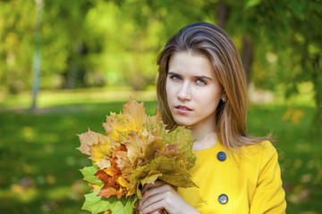 Naklejka premium Happy young woman in yellow coat in autumn park