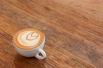 Hot cafe latte wirh latte art on wooden table