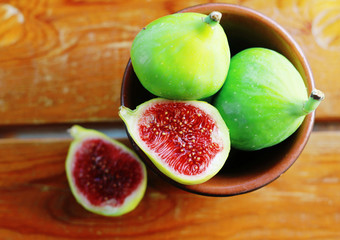 Fresh green figs in a bowl on rustic wooden table