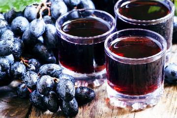 Fresh dark grape juice and fresh berries on old wooden table, se