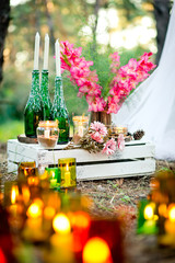 Wedding decor with the burning candles, bottles, gladiolus.