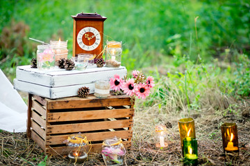 Decoration of a wedding photoshoot with boxes, the burning candles, clock, cones