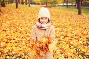 smiling little girl with autumn leaves in park