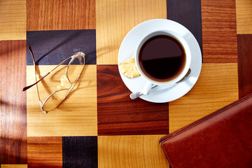 Coffee cup with glasses and leather folder on table retro