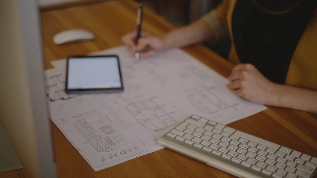 Young female architect working on blueprint