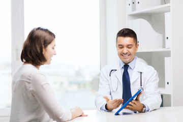 smiling doctor and woman with tablet pc at clinic