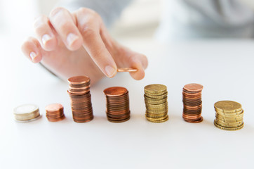 close up of female hand putting coins into columns