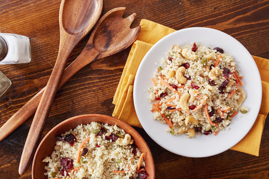 Couscous Cold Salad With Nuts, Seeds, Cranberries And Carrots Being Served On A Plate From Bowl Overhead Photo