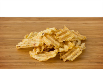 Close-up of heap of potato chips on a wooden board. Copy space.