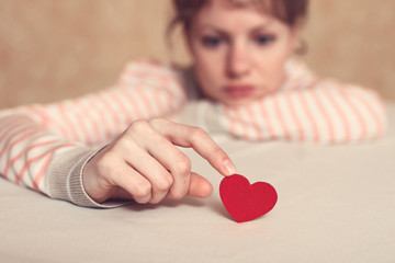 Upset and sad girl is touching heart symbol with finger