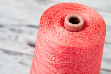 Spool of Synthetic Pink Thread on White Wooden Background
