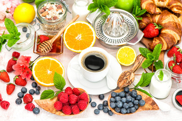 Breakfast with coffee, croissants, granola, honey, berries, frui