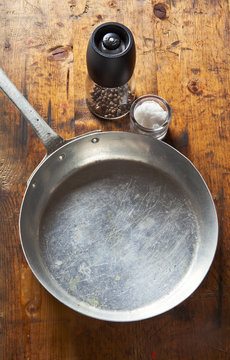 an empty pan on a wooden table. salt, pepper, olive oil. space f