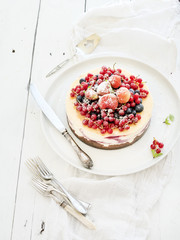 Cheesecake with fresh garden berries on top over white wooden