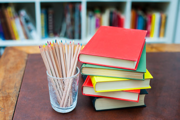 Colored pencils with pile of books with colored covers