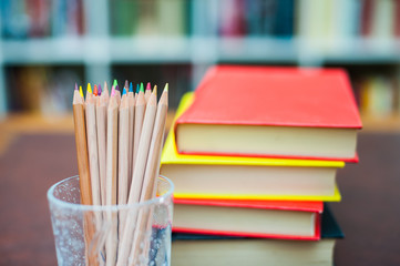 Colored pencils with pile of books in background