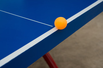 pingpong ball hits the edge of a blue pingpong table
