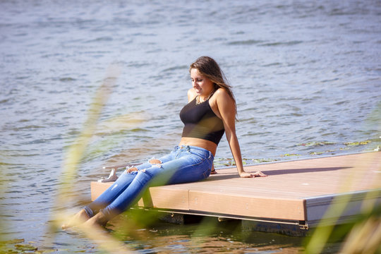 Adolescente de 15 años en el embarcadero. Chica rubia adolescente pasando una tarde de verano junto al rio.