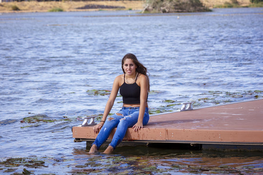 Adolescente de 15 años en el embarcadero. Chica rubia adolescente pasando una tarde de verano junto al rio.