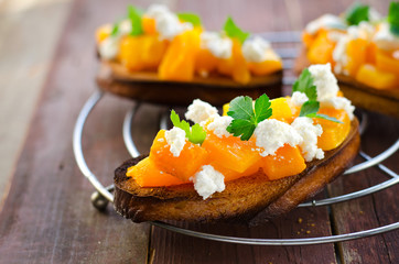 Bruschetta with chunks of pumpkin, goat cheese and parsley