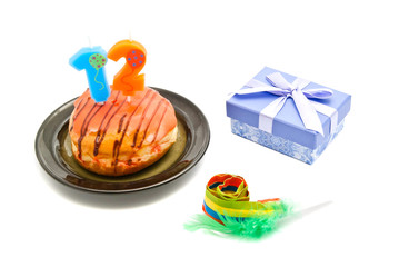 donut with twelve years birthday candle, whistle and gift on whi
