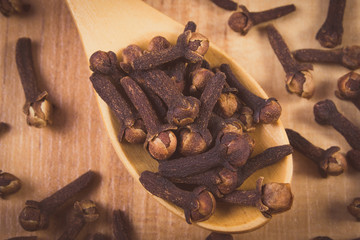 Vintage photo, Heap of cloves with wooden spoon on table, seasoning for cooking