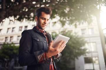handsome man in down town los angeles using tablet on the go