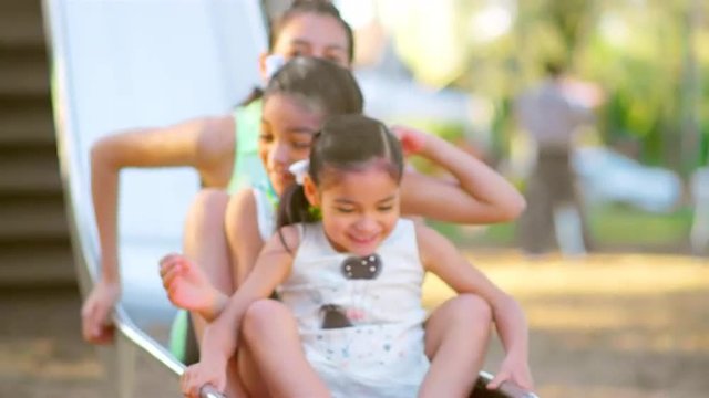 Young girls going down a slide together at a park
