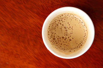 Hot coffee in paper cup seen from top.