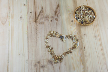 Heart-shaped muesli and cereal on the wooden table.