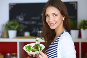 Young woman eating salad and holding a mixed salad 