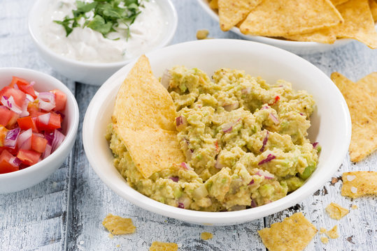 spicy avocado sauce and assorted sauces with corn chips on white