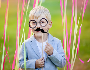 Fototapeta na wymiar little boy with funny paper mustache and glasses